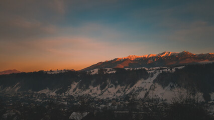 Winter landscape with high and snowy rocky mountains. Amazing sunset in shades of purple in the evening sky