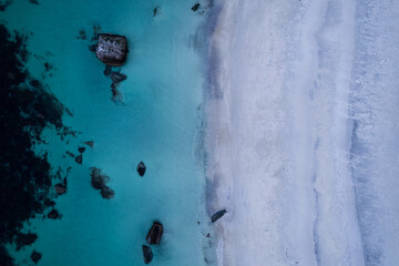 Aerial of Haukland beach in Northern Norway located in the Arctic Circle.  This was shot on a drone in the fall.  This beach has white sand, crystal turquoise clear blue water, and large rocks.