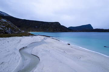 Aerial of Haukland beach in Northern Norway located in the Arctic Circle.  This was shot on a drone in the fall.  This beach has white sand, crystal turquoise clear blue water, and large rocks.