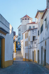The view of narrow paved street of Evora with the cozy white and yellow houses, Evora, Alentejo, Portugal