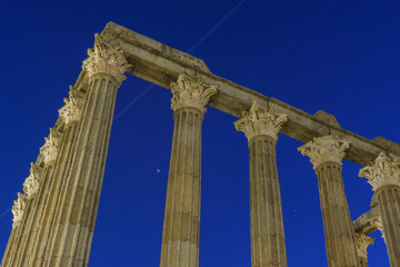 Fototapeta na wymiar Columns of ruins of ancient roman temple of Diana during evening twilight with planets Jupiter and Saturn on the blue sky, Evora, Alentejo, Portugal