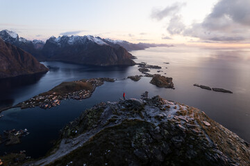 Aerial of Reinebringen mountain hike in Lofoten, Norway at sunrise / sunset.  Snowcovered mountains captured on image by a drone.  Located far North in the Arctic Circle.