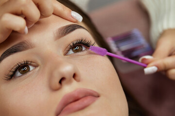 master combs the eyelashes of the client after the eyelash extension procedure. close-up. Cosmetology and skin care