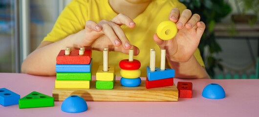 eco wooden toys. The child collects a sorter. Educational logic toys for kids. Games for Child...