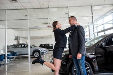 happy young couple chooses and buys a new car for the family at a car dealership.