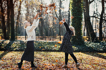 Autumn family walk. Heartwarming moment of smiling mother lovingly placing autumn leaf in daughters...