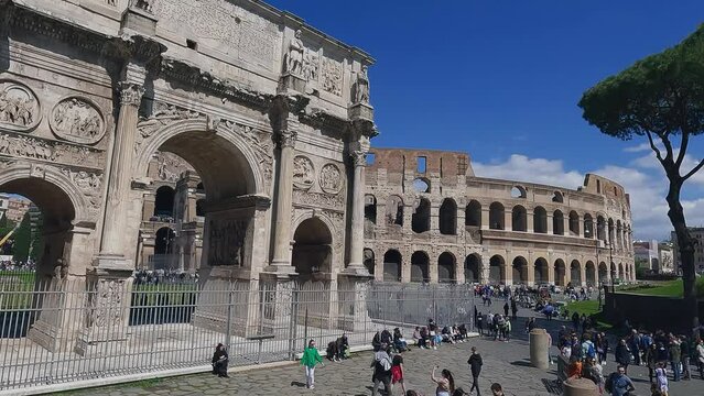 Aerial drone shot of Arch of Constantine And The Colosseum with tourists viewed from via di S. Gregorio on sunny day, slow motion