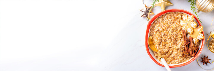 Christmas morning gingerbread oatmeal breakfast. Spice sweet oatmeal with gingerbread crumbs, cinnamon and honey, on festive decorated background copy space