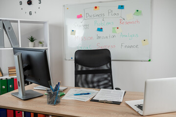 modern office workplace desk with laptop and financial diagrams, against flipchart on wall