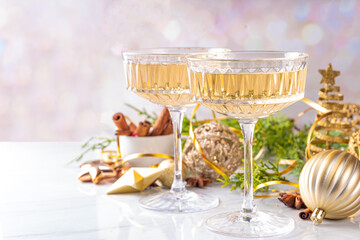 Two champagne glasses on Christmas decorated background, Merry Christmas and Happy New Year greeting card background, with golden baubles and fir tree branches