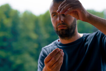 a young man strings a fishing line or a fly on a hook for fishing feeder free style method