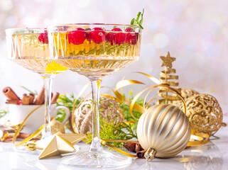 Christmas champagne fruit punch with cranberry, orange, spices and rosemary. Sweet alcohol cocktail glasses, on Christmas and New Year decorated background