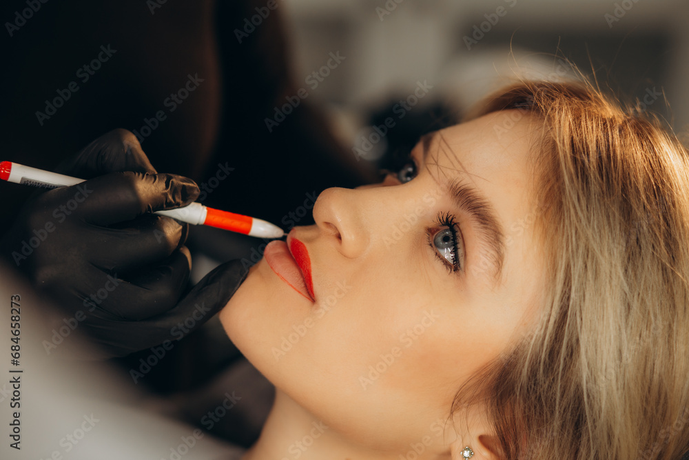 Wall mural cosmetologist in black gloves making permanent makeup on woman's lips with tattoo pen machine. micro