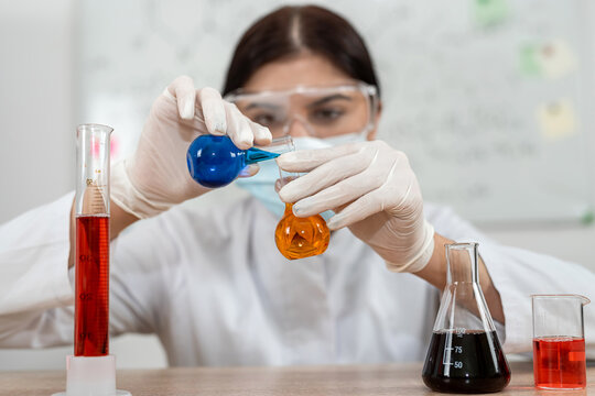 caucasian woman scientist mixed liquid from flask into beaker