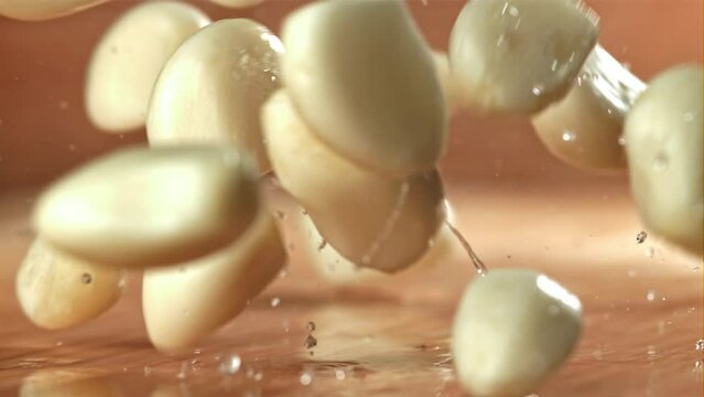 Fresh garlic falls on a wet cutting board. Filmed on a high-speed camera at 1000 fps. High quality FullHD footage