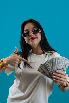 Happy caucasian woman is holding a lot of dollar banknotes isolated on blue