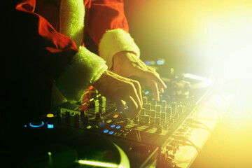 Santa Claus DJ mixing music on a Christmas party in bright stage lights.