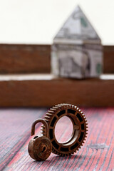 lock and keys with miniature house made of dollar bills on wooden background