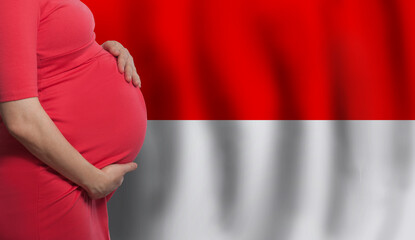 Pregnant woman belly on flag of Monaco background