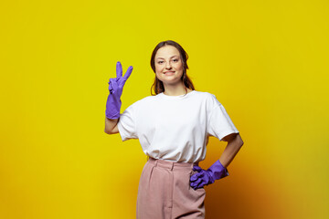 Сleaning concept. Young woman in blue glowes on bright yellow studio wall background