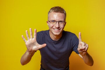 Portrait of casual man showing fingers number six while smiling confident and happy isolated on...