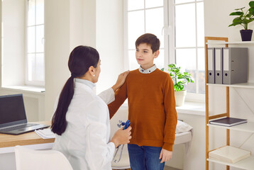Female pediatrician comforting preteen boy in medical office. Doctor, GP examining and talking with boy patient during medical pediatric checkup in clinic. Children medical care concept