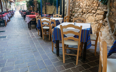 Outdoors traditional tavern restaurant Chania Old Town, Crete island Greece. Potted plant on alley.