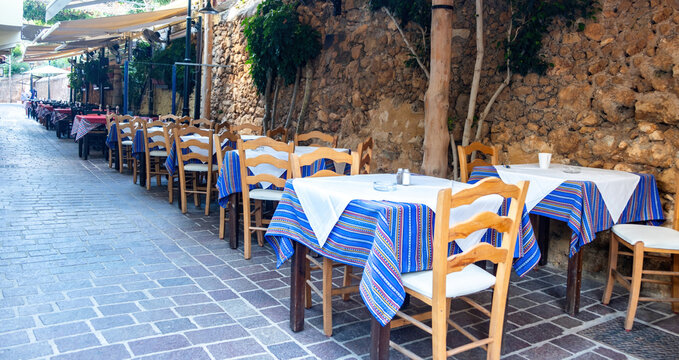 Outdoors traditional tavern restaurant Chania Old Town, Crete island Greece. Potted plant on alley.