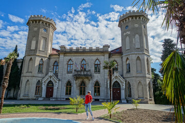 Fototapeta premium A woman on the background of a view of the Yusupov Palace in Koreiz, Bolshaya Yalta, Russia. Prince Yusupov's Palace on a sunny summer day. Mishor, Crimea