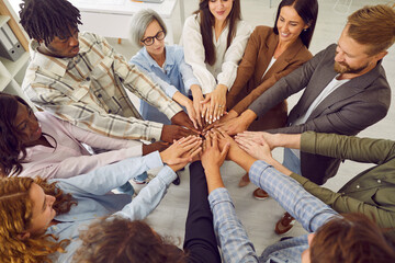 Top view photo of diverse business people men and women putting their arms together. Stack of hands...
