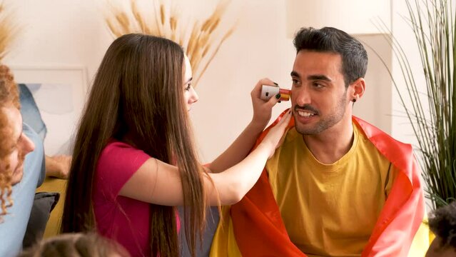 Friends paint their face with Spain flag colors to support their team during the World Cup.