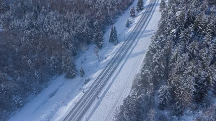 Poster Top view of train track rails crossing through snowy forest in winter near Munich © Pablo