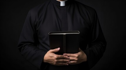 Catholic priest in black robe holds Holy Bible standing in old rural church closeup