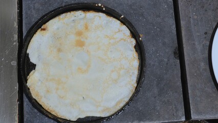Large round pancake in a frying pan. Cooking smoke goes up from the pancake. Shrovetide holiday, a vital holiday of the meeting of spring among the Slavs.