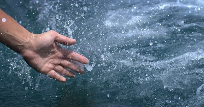 Woman hand touching pure water during holidays in boat and she's refreshing with sea waves during the trip.