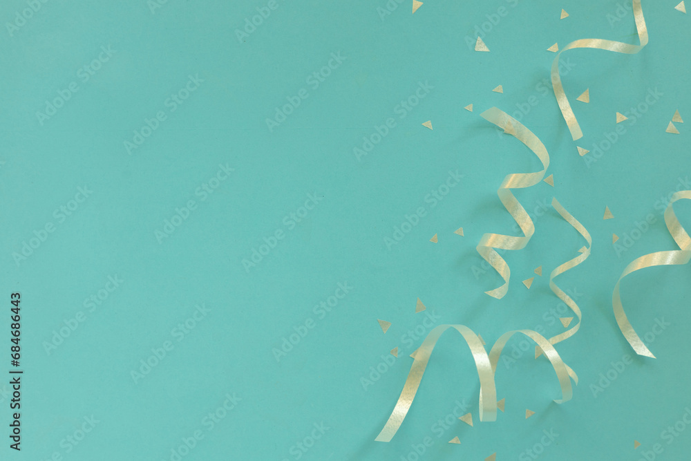 Wall mural close up on group of silver color of rolling ribbon and confetti on teal background with copy space 