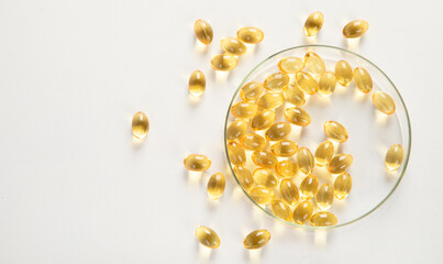 Yellow pills in petri dish on white background. Omega.