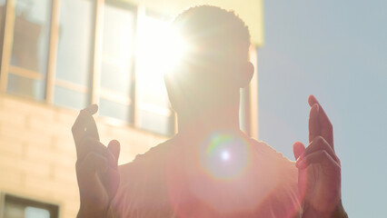 African American man male silhouette in sunshine sun sunny sunbeam background guy crossing fingers...