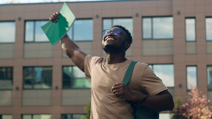 Overjoyed biracial male student guy high school pupil African American man in city outdoors scream passing exam getting good grade excited feel euphoric achievement education study success scholarship - obrazy, fototapety, plakaty