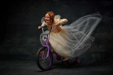 Charming little princess, dressed like medieval person riding children's bicycle and having fun...