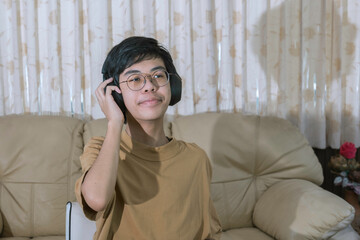 Young boy modern wireless headphones relax sitting on couch or sofa listening to music, enjoying meditation for sleep and peaceful mind, happy calm young boy in earphones rest on cozy sofa.