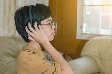 Young boy modern wireless headphones relax sitting on couch or sofa listening to music, enjoying meditation for sleep and peaceful mind, happy calm young boy in earphones rest on cozy sofa.