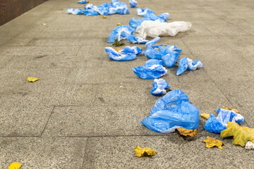 Plastic shoe covers scattered in form of path. Ecology issues. Environmental pollution.