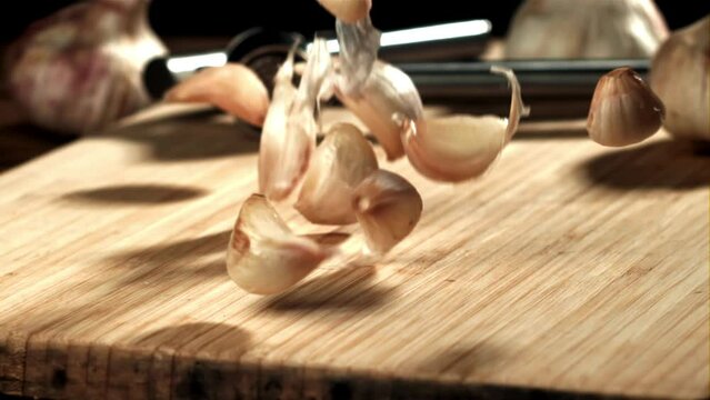 Fresh garlic falls on a cutting board. Filmed on a high-speed camera at 1000 fps. High quality FullHD footage