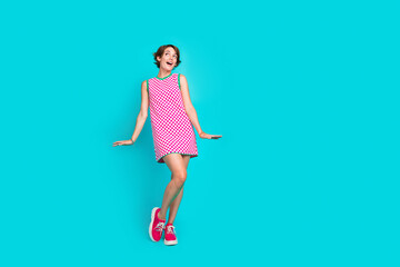 Full length photo of adorable cheerful girl wear stylish checkered clothes loo up empty space poster ad isolated on cyan color background