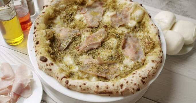 Pizza with Meat, Pesto, Cheese and Parmesan fresh out of the oven ready to eat. Delicious Italian pizza. Napoli Pizza. Food Service on white table and ingredient. Tasty Pizza with Cheese and Parmesan.