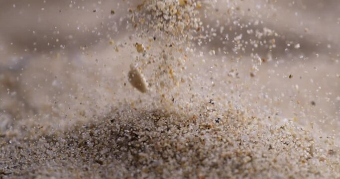 Particles of dry sand are pouring down forming hill at 1000 fps. Close up shot of crumbling natural sand grains, sandy dune. Heap of petrified natural mineral.