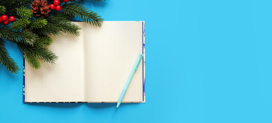 Open notebook with pen on a blue background, spruce branch, top view, empty space. Copy space. Christmas branch and diary for notes
