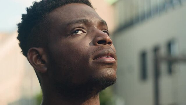 Moving shot close up inspired contemplating biracial guy pensive thinking man looking around on urban city building skyscrapers think look up in sky outdoors business African American male dreaming