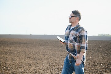 A farmer works in a field sown in spring. An agronomist walks the earth, assessing a plowed field in autumn. Agriculture. Smart farming technologies.